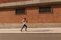 Side view of blonde girl jogging on sidewalk — Stock Photo