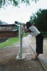 Vue latérale de la femme brune regardant une machine binoculaire touristique dans le parc . — Photo de stock