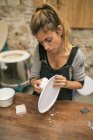 Portrait of concentrated potter creating plates from white clay. — Stock Photo
