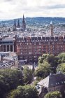 EDINBURGH, SCOTLAND - AUGUST 27, 2017: Picturesque cityscape over green hill and cloudy sky on background — Stock Photo
