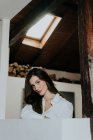 Affascinante ragazza bruna in camicia bianca in posa a casa — Foto stock