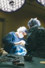 Крупный план стола с хирургическими инструментами поверх врачей, оперирующих пациента на заднем плане — стоковое фото