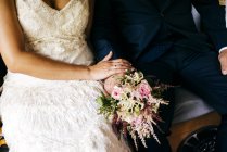 Mittelteil Frau und Mann in eleganten Hochzeits-Outfits sitzen zusammen auf Bank. — Stockfoto