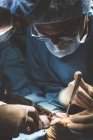 Cirurgiões de cultura concentrados em paciente operando uniforme com instrumentos especiais . — Fotografia de Stock