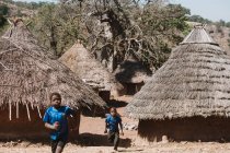 Goree, senegal- 6. Dezember 2017: Kinder rennen bei strahlendem Sonnenschein zwischen Bungalows in ihrem Heimatdorf. — Stockfoto