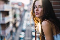 Young brunette girl posing romantically on balcony and looking at camera — Stock Photo