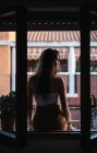 Vista posteriore della ragazza bruna seduta sul davanzale della finestra al balcone — Foto stock