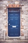 Внешний вид фасада здания с голубой дверью в кирпичной стене — стоковое фото