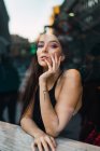 View through window to brunette girl looking at camera — Stock Photo