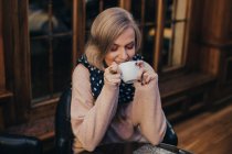 Portrait of blonde girl drinking cup of tea at cafe — Stock Photo
