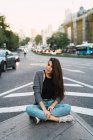 Brunette fille en tenue décontractée assis à côté marcher sur la scène de rue — Photo de stock