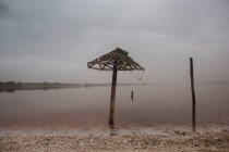 Vista para guarda-chuva palha danificada em pé na praia vazia — Fotografia de Stock