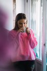 Portrait of woman in pink sweatshot having coffee at home — Stock Photo