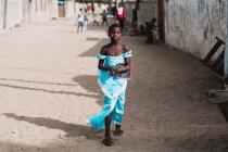Goree, Senegal- December 6, 2017:Girl walking in blue dress on street of poor town. — Stock Photo