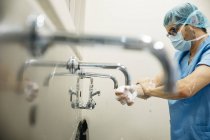 Seitenansicht des durchdachten Chirurgen, der sich vor der Operation die Hände wäscht — Stockfoto