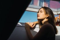 Jeune femme regardant loin et posant près de la fenêtre — Photo de stock