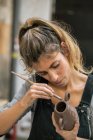 Selbstbewusste Frau glasiert Tontopf mit Pinsel — Stockfoto