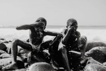 Goree, Senegal- December 6, 2017: Cheerful black kids washing faces on rock in waves — Stock Photo