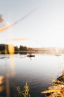 Paesaggio di tranquille acque del lago nella foschia del mattino con i viaggiatori che remano in kayak . — Foto stock