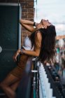 Seitenansicht des stilvollen brünetten Mädchens lehnt am Balkonzaun — Stockfoto