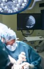 Monitor médico detrás de cirujanos que proporcionan operación en la sala de cirugía - foto de stock