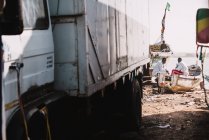 Goree, senegal- 6. Dezember 2017: Fernsicht von Männern, die auf Booten am Strand in der Nähe parkender Lastwagen sitzen und reden — Stockfoto