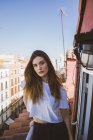 Confident brunette girl posing on balcony and looking at camera — Stock Photo