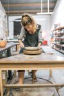 Вид спереду жіночого гончарного формування глиняної пластини з інструментом на майстерні — стокове фото