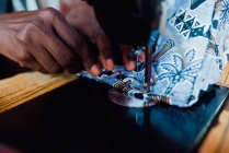 Обрізати руки шити одяг зі світло-блакитної тканини на старій швейній машині . — стокове фото