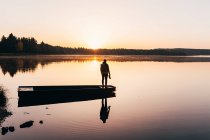 Silhouette dell'uomo in piedi sulla barca sul lungolago nella foschia del mattino — Foto stock