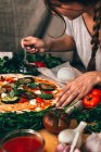 Casual woman pouring pizza with delicious sauce while cooking. - foto de stock