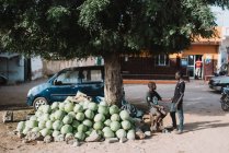 Goree, Sénégal- 6 décembre 2017 : Vue latérale de jeunes garçons communiquant tout en vendant des fruits dans la rue dans un quartier pauvre de la ville . — Photo de stock