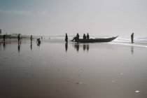 Goree, senegal- 6. Dezember 2017: Silhouetten afrikanischer Menschen, die abends auf einem Boot am Sandstrand stehen. — Stockfoto