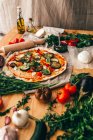 Низкий угол обзора пиццы и ингредиентов на деревянном столе — стоковое фото