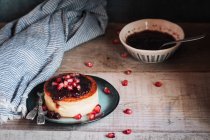 Käsekuchen mit Beeren-Marmelade und Granatapfel im rustikalen Teller — Stockfoto
