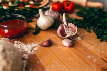 Ripe garlic and pizza ingredients on wooden board — Stock Photo