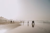 Yoff, Sénégal- 6 décembre 2017 : Paysage de rivage tropical avec plage de sable fin et personnes marchant dans la brume de la lumière . — Photo de stock