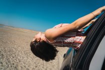 Vista laterale della donna appesa fuori di equitazione nel deserto finestrino auto — Foto stock