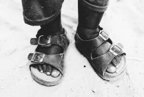 Cultiver les pieds d'enfant en sandales sur sable — Photo de stock