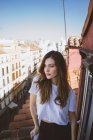 Menina morena em t-shirt branca posando na varanda e olhando para longe — Fotografia de Stock