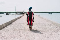 Back view of African woman in ethnic clothes walking on pier. — Stock Photo