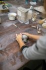 Über-Schulter-Ansicht einer Töpferin beim Kneten von Ton auf Holztisch — Stockfoto