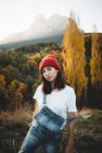 Hübsche junge Frau mit rotem Hut posiert vor dem Hintergrund der herbstlichen nebligen Landschaft — Stockfoto