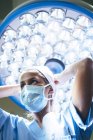 Високий кут зору жінки в масці в хірургічній кімнаті — стокове фото