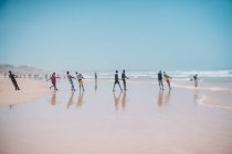 Goree, Senegal- December 6, 2017: Row of people standing at seashore and pulling rope on sandy beach. — Stock Photo