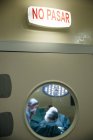Vista a través de la ventana de la puerta a los cirujanos en el quirófano - foto de stock