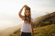 Молода жінка торкається волосся на пагорбі — стокове фото