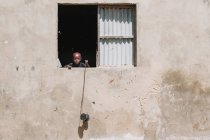 Goree, Sénégal- 6 décembre 2017 : Petit Africain regardant par la fenêtre et tenant une bobine — Photo de stock