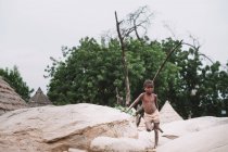 Goree, senegal- 6. Dezember 2017: kleines Kind lehnt auf einem Felsen über den Dächern von Dorfbungalows . — Stockfoto