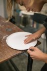 Ritratto di donna concentrata che si piega sul piatto e lo forma da argilla bianca . — Foto stock